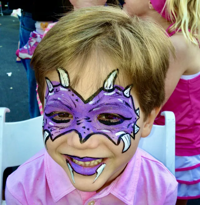 A face painter creating a colorful design for a young guest