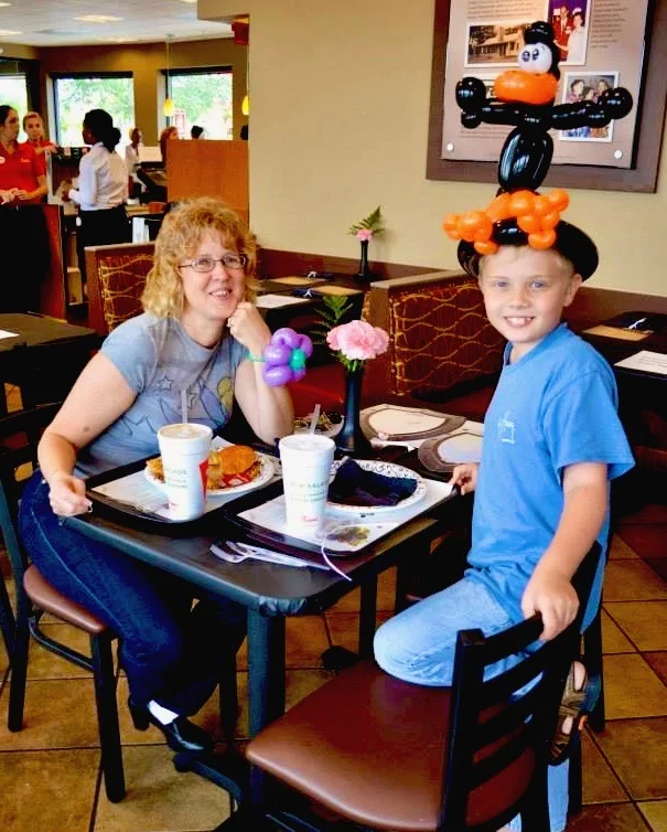 A mother and son enjoying balloon creations during a restaurant family night