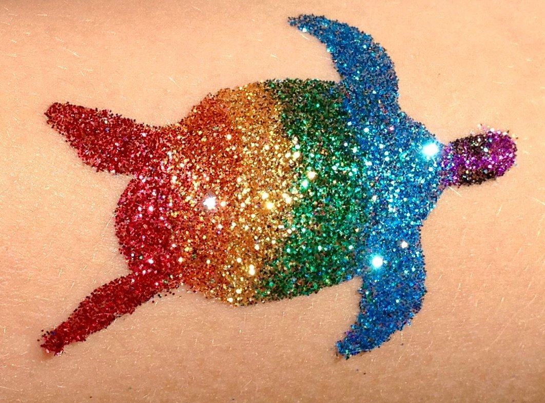A rainbow glitter turtle design applied to a guest's skin.