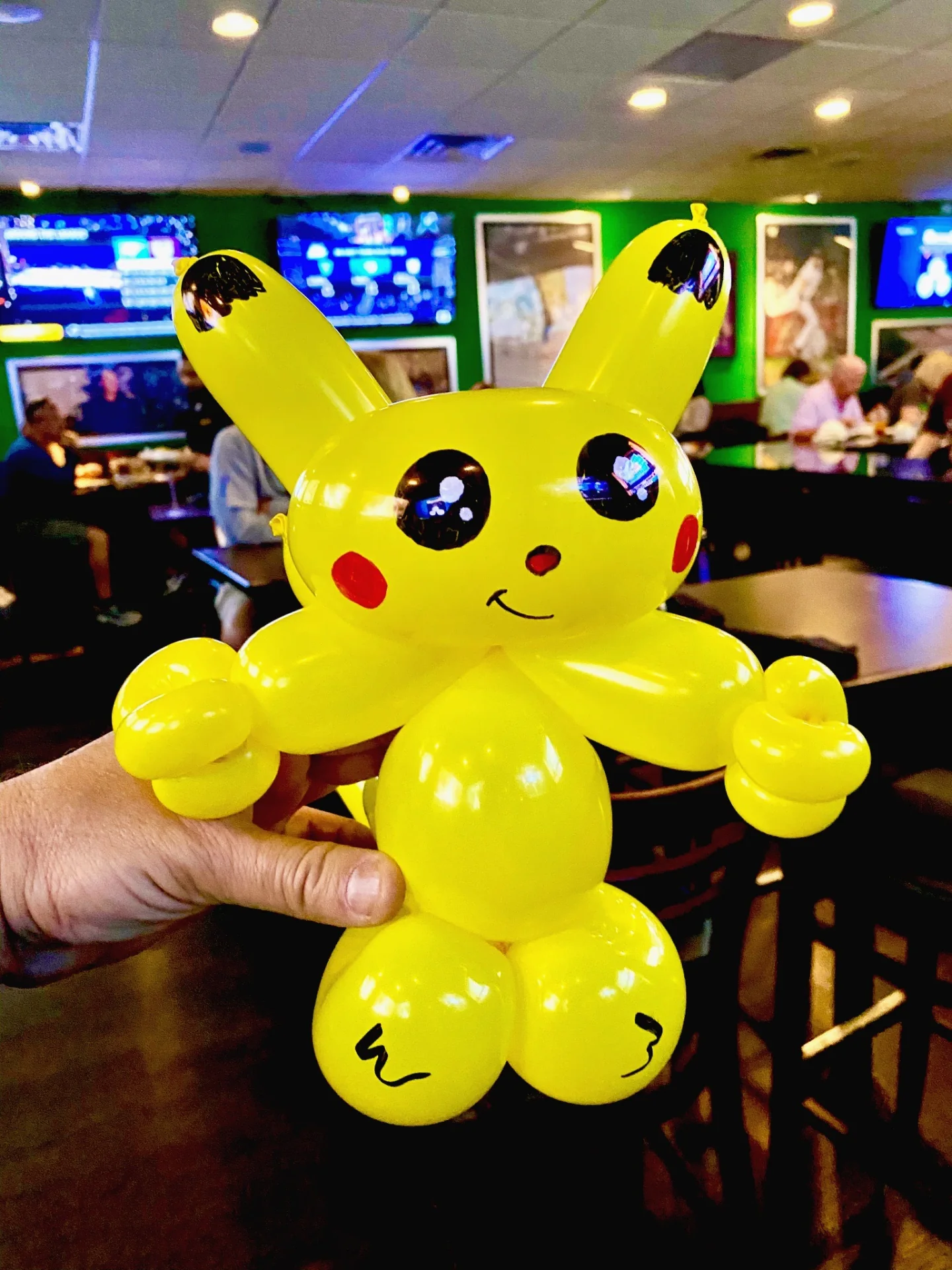 A detailed yellow character-shaped balloon sculpture held inside a restaurant.